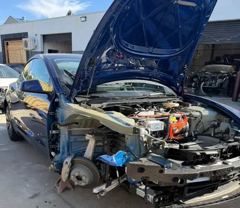 Blue Tesla with the front end taken apart for collision repair